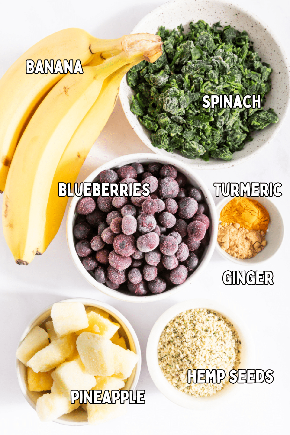 Bowls of ingredients for make ahead smoothies: spinach, banana, pineapple, blueberries, hemp seeds, ground ginger, ground turmeric.