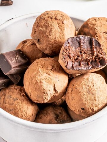 Bourbon truffles in a white bowl with a few squares of chocolate.