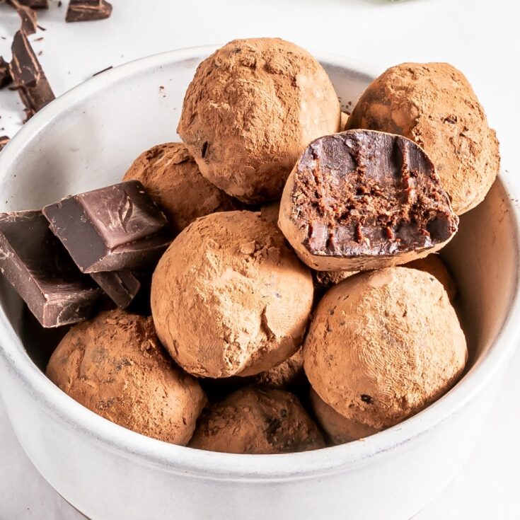 Bourbon truffles in a white bowl with a few squares of chocolate.
