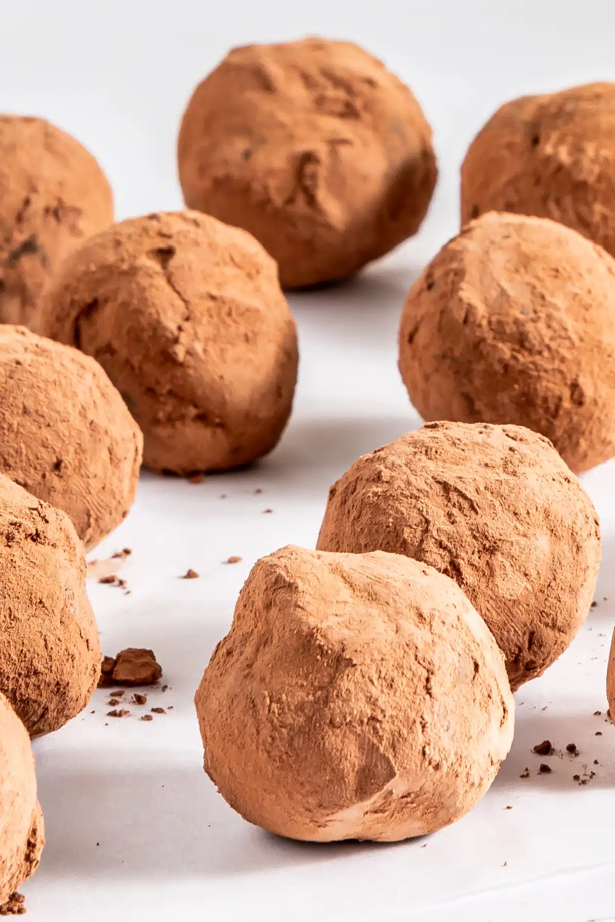 Close up of bourbon truffles on a white tabletop.