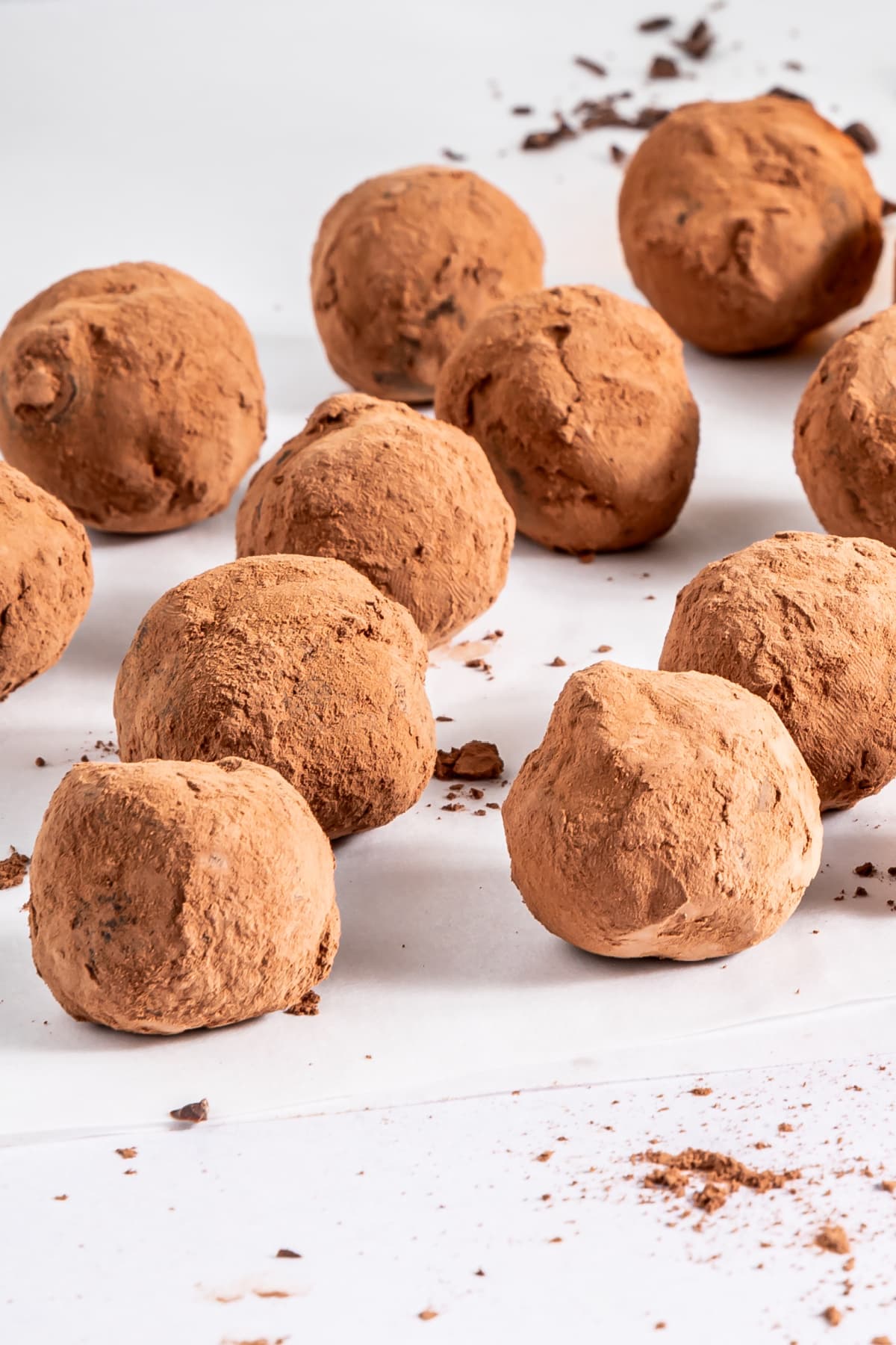 Bourbon balls and some chopped chocolate on a white tabletop.