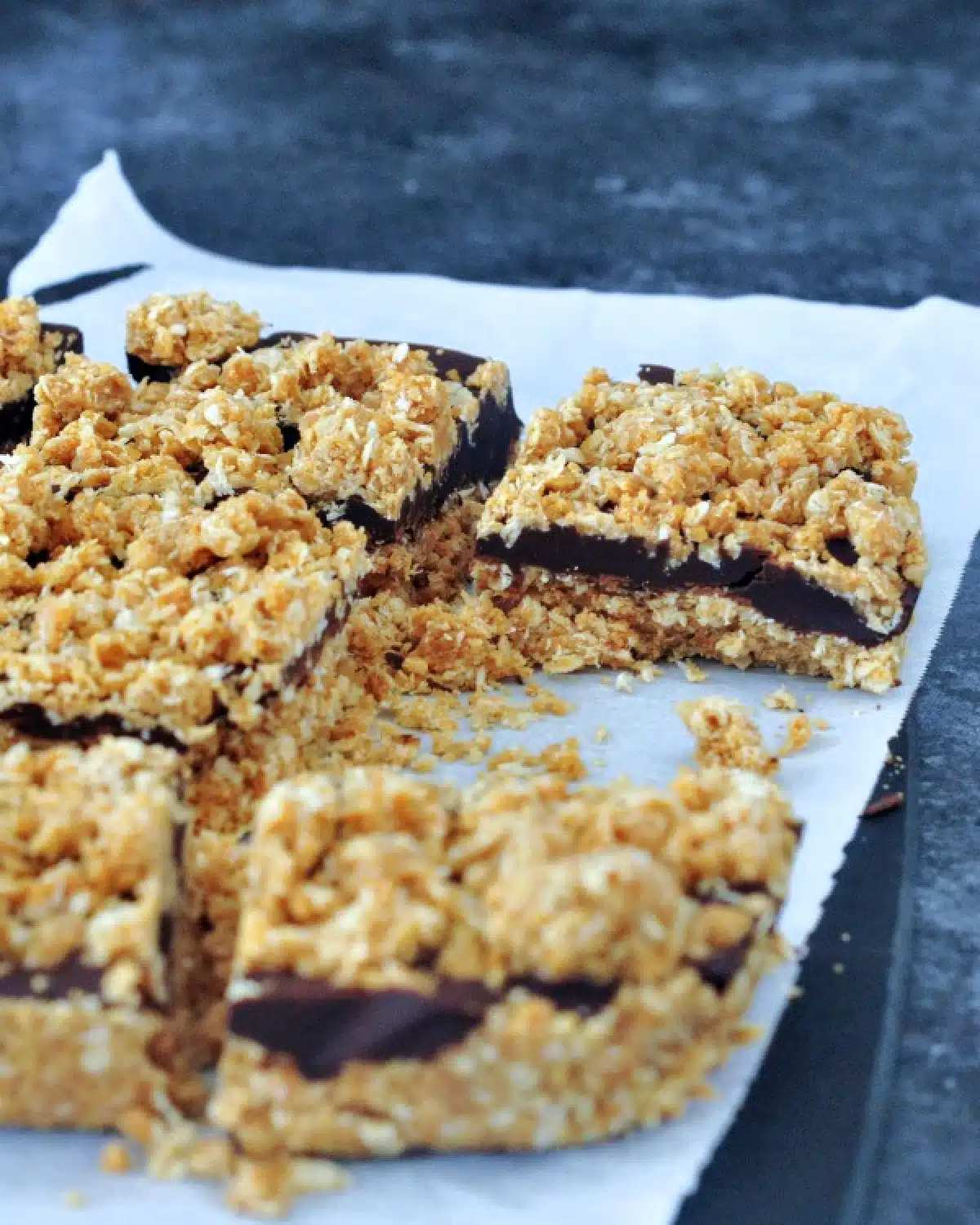 Chocolate oat no bake bars on parchment, just after baking and cut into squares.