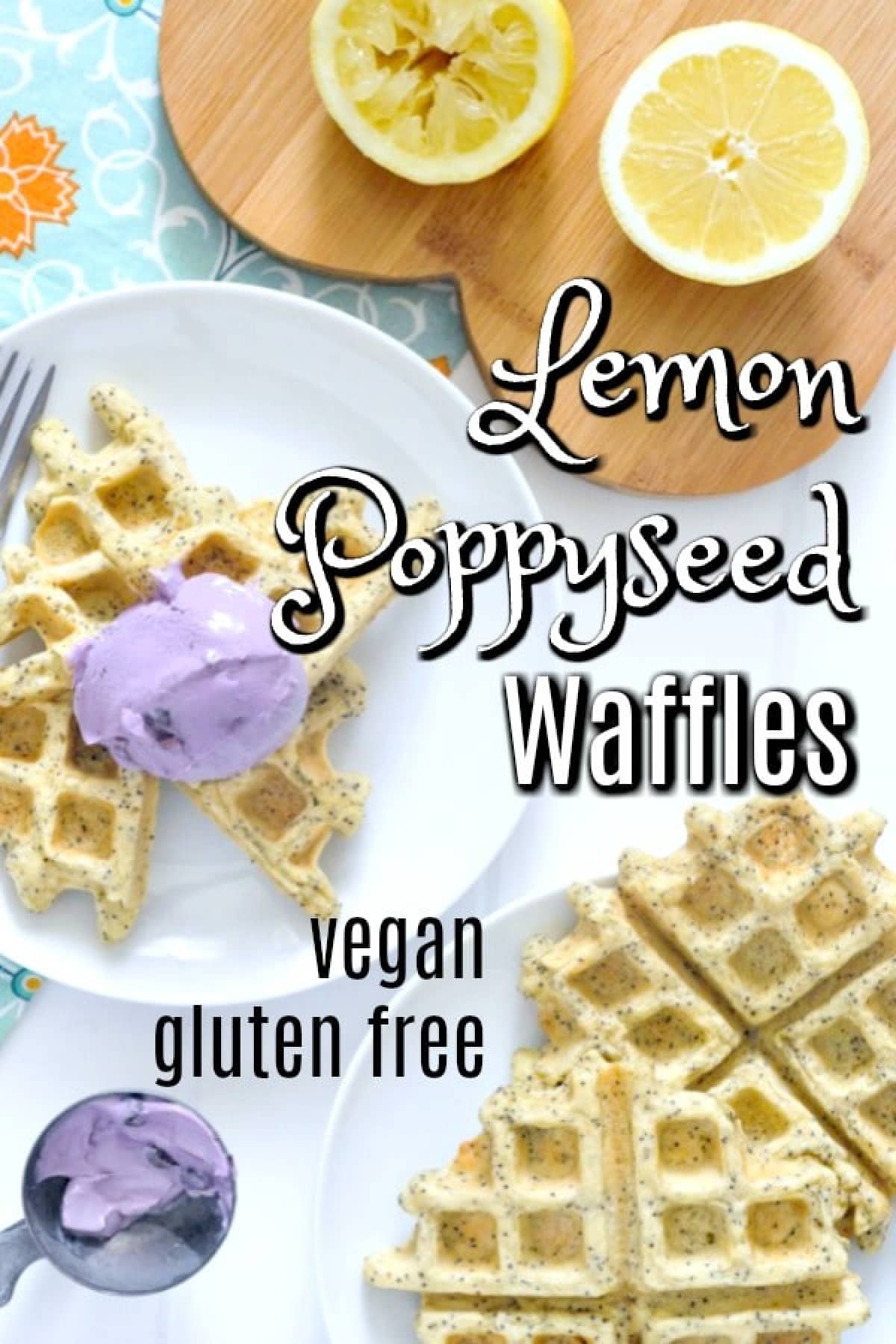 Overhead view of golden yellow lemon poppyseed waffles on a white plate topped with a scoop of light purple blueberry yogurt. A heart shaped wood board holds two fresh lemon halves, one squeezed. Another white plate holds 2 more full Belgian style waffles, and an ice cream scoop sits to the side with purple yogurt in it.