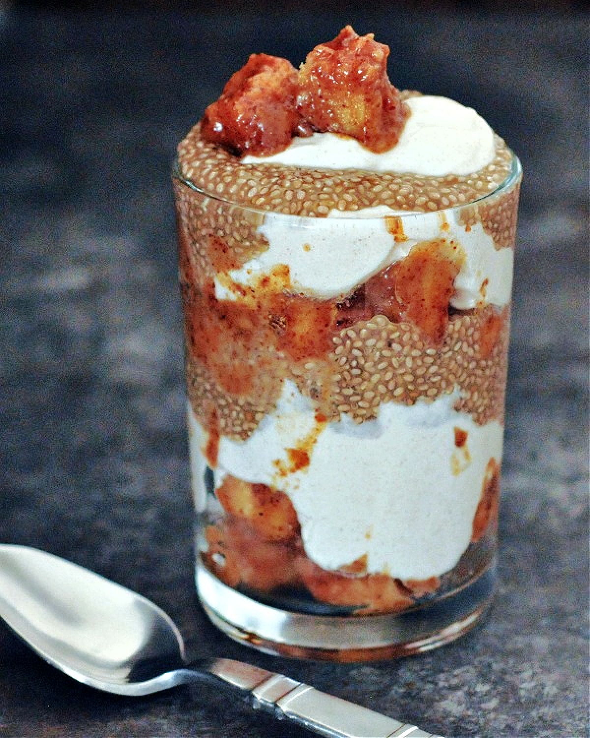 Roasted apples and chia pudding layered with yogurt and cubed apple in tall glass.