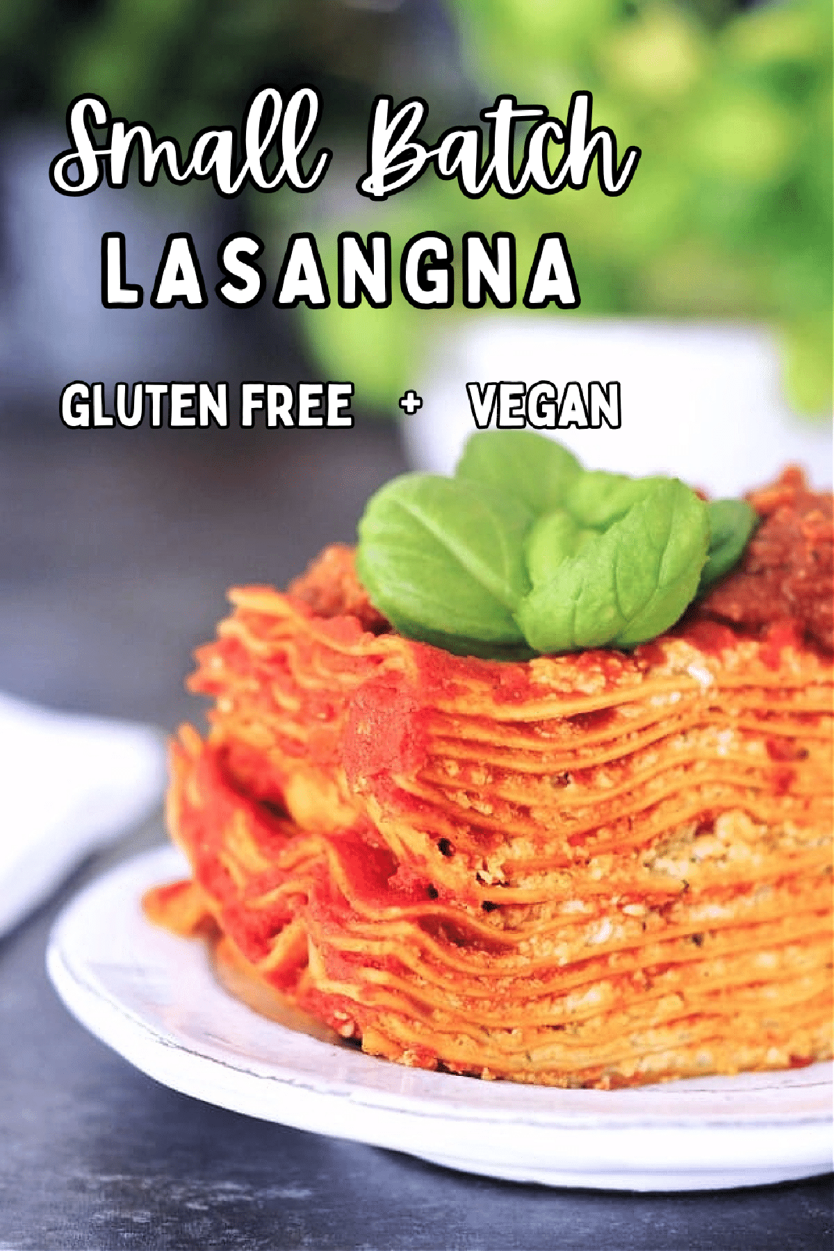 Twelve layer slice of gluten free Vegan Lasagna on a rustic plate, garnished with fresh basil.