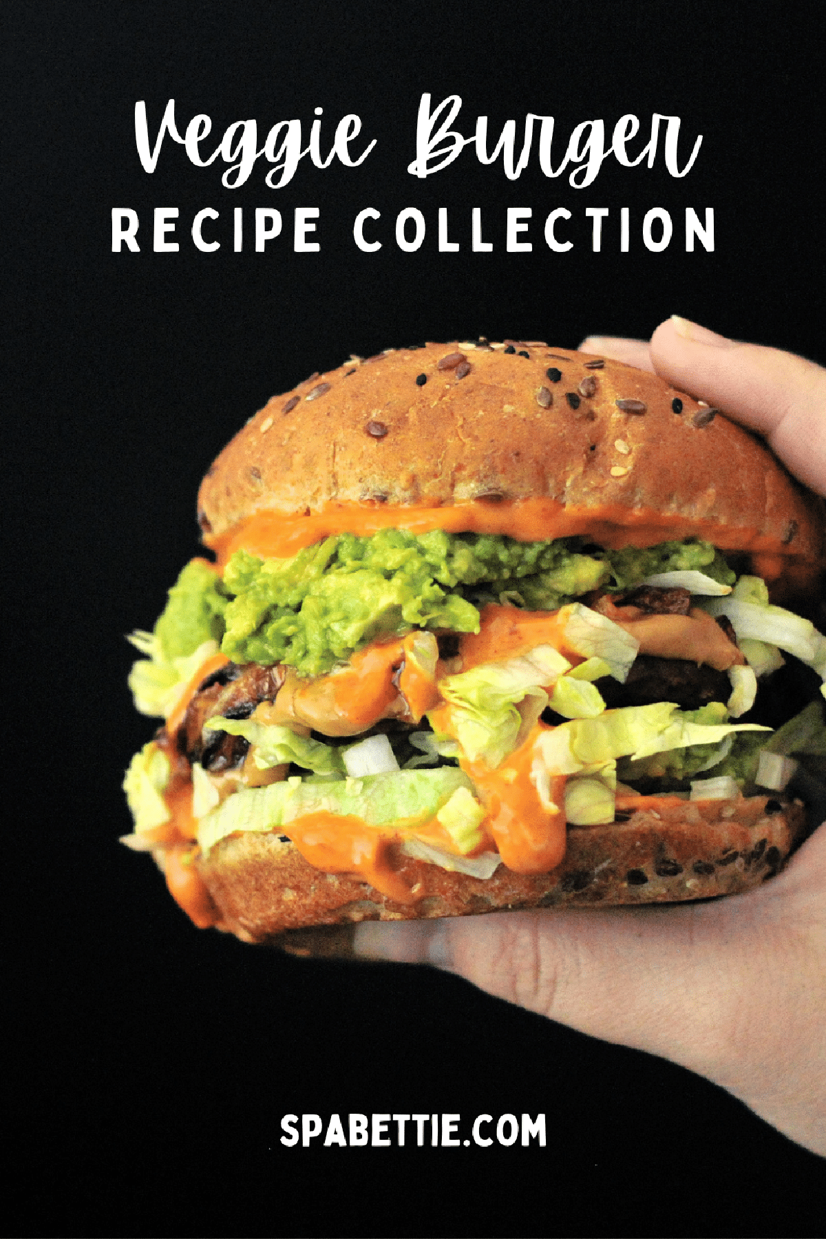 A spicy peanut butter burger held in a hand against a black background; burger has bright orange spicy kimchi sauce, shredded iceberg lettuce, a veggie patty, mashed avocado, and a seeded bun.