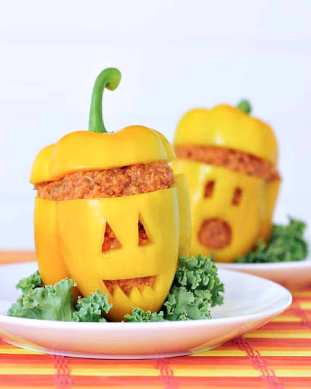 Two yellow bell peppers with the top sliced off and filled with a pizza flavored polenta. Peppers are carved with a jack o lantern faces for Halloween.
