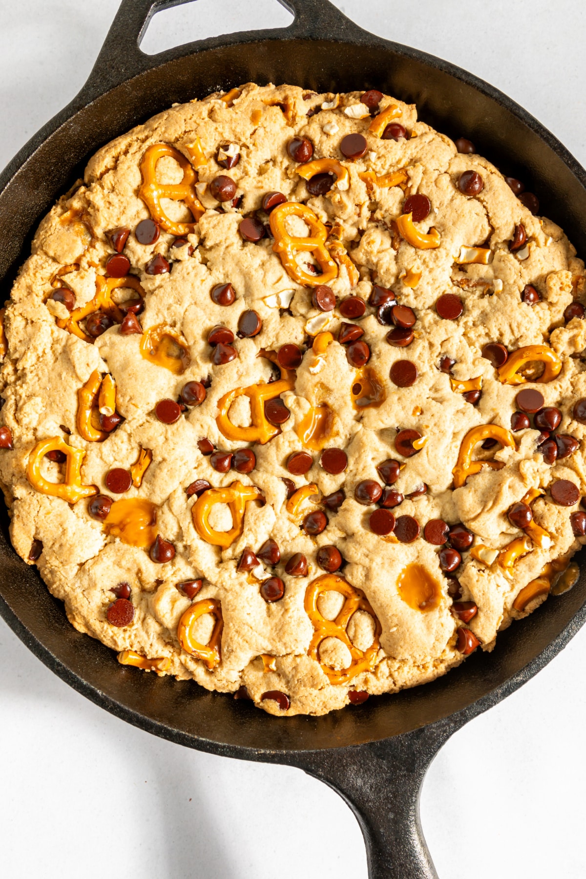 Overhead view of a baked skillet cookie with caramel, pretzels, and chocolate chips.