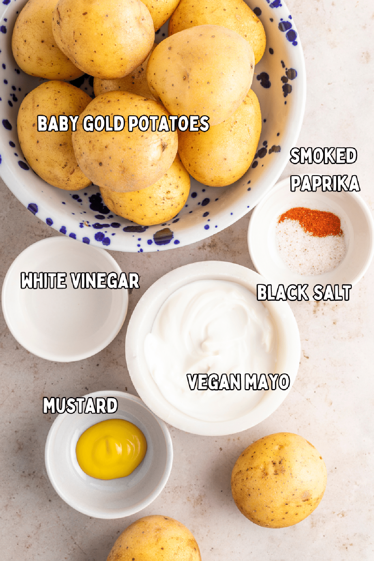 Overhead view of ingredients to make deviled egg potatoes: baby gold potatoes, white vinegar, vegan mayo, mustard, black salt, and smoked paprika.