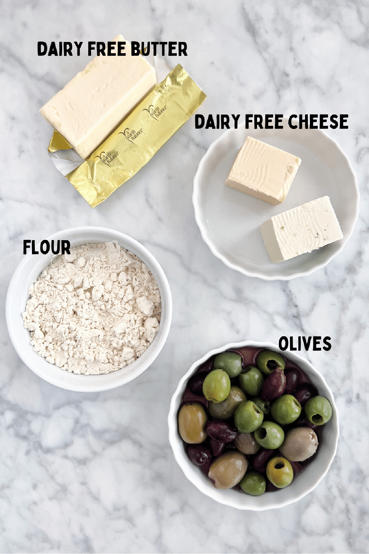 Overhead view of ingredients to make olive cheese bites: flour, olives, dairy free butter and cheese.