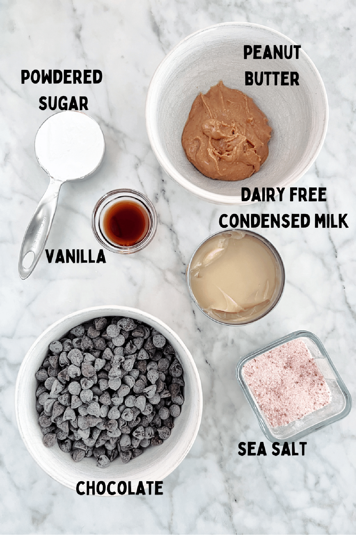 Overhead view of ingredients to make peanut butter fudge: peanut butter, powdered sugar, condensed milk, vanilla, sea salt, and chocolate.