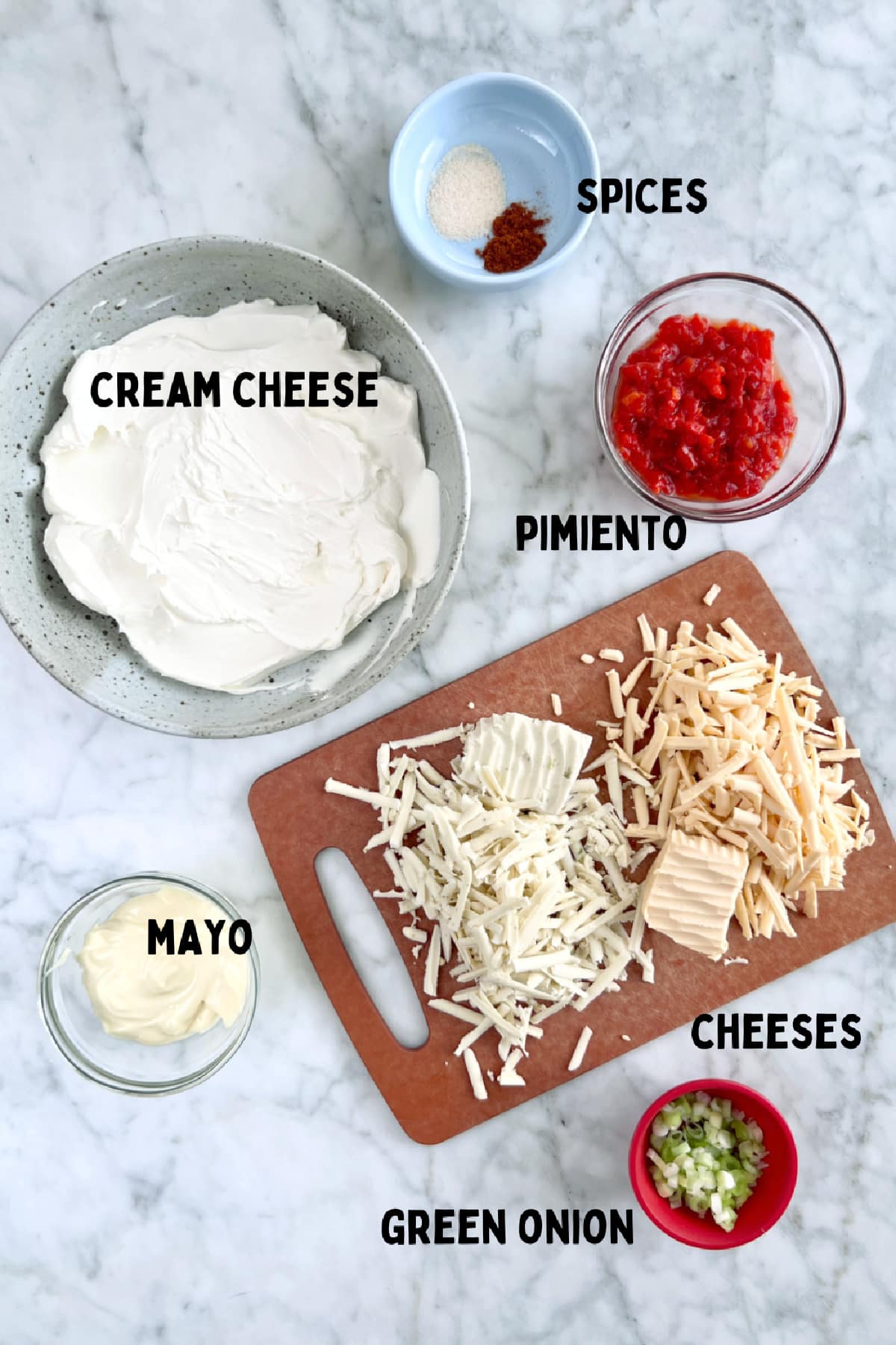 Ingredients to make pimiento cheese: cream cheese, grated cheese, spices, pimiento, mayo, and green onion.