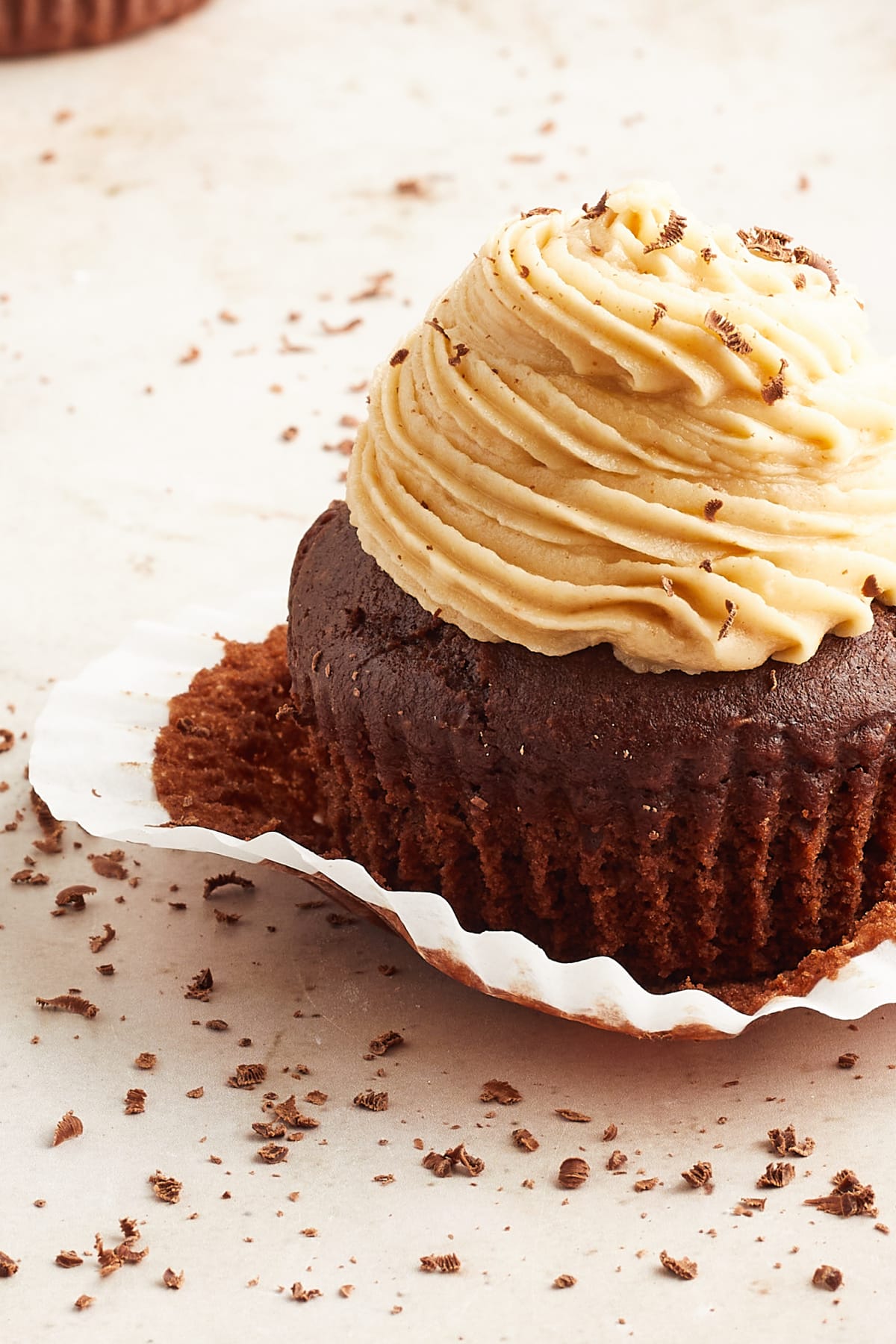 One chocolate cupcake with peanut butter frosting piped on top. The white paper wrapper is partially removed.