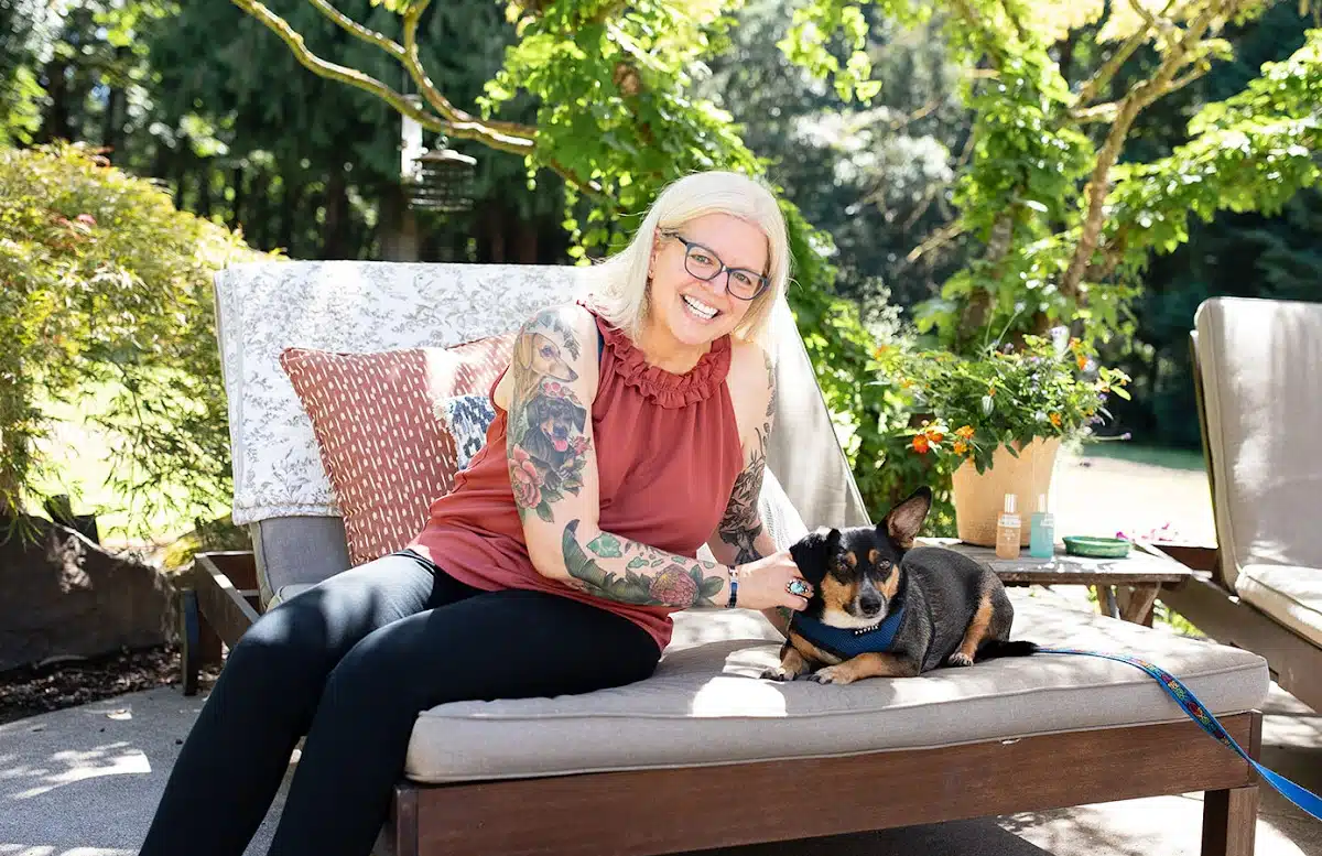 Kristina sits on a deck chair in the back yard with her dog, Dutch.