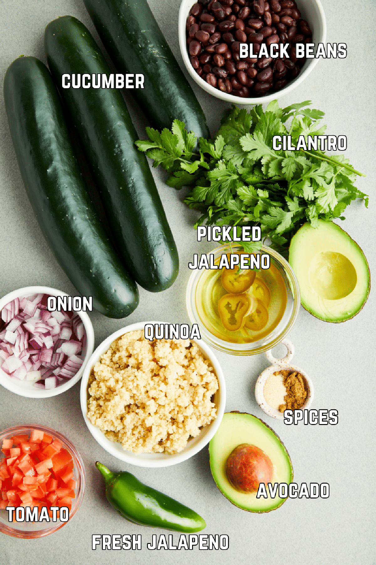 Ingredients to make tex mex cucumber boats: cucumbers, black beans, fresh herbs, pickled and fresh jalapeno, avocado, spices, quinoa, onion, and tomato.