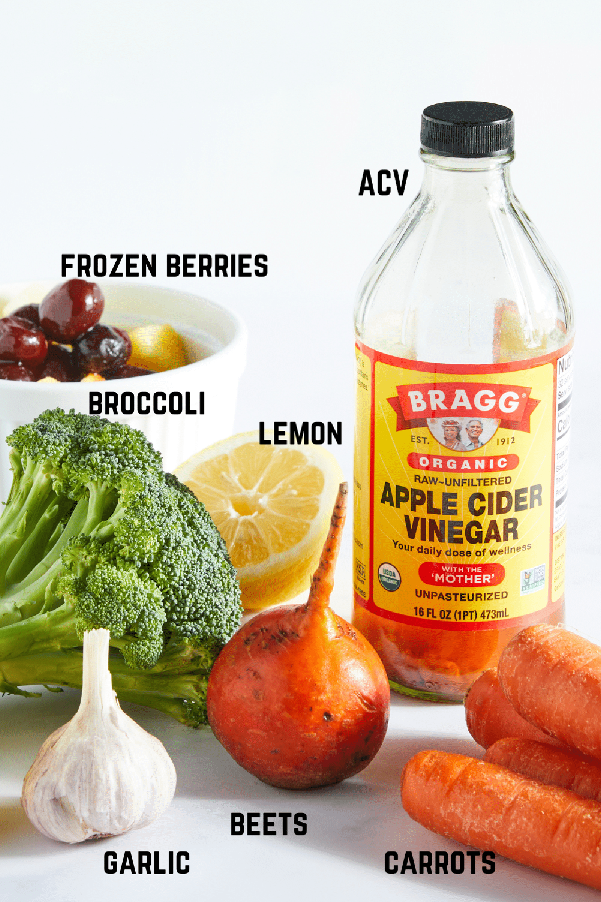 Ingredients to make immune boosting juice we call healthy defense juice: frozen berries, fresh broccoli, garlic cloves, golden beets, carrots, lemon, and apple cider vinegar.