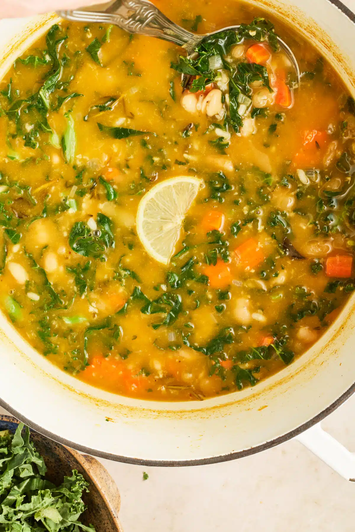 An overhead view of a pot of white bean soup with a spoon in it.